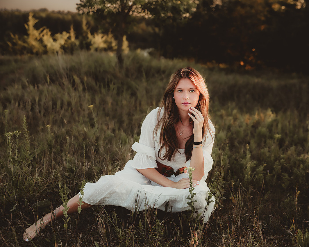 senior girl portrait Sioux Falls South Dakota wearing white dress wearing jewelry and belt in sunlit field, backlit outdoor session