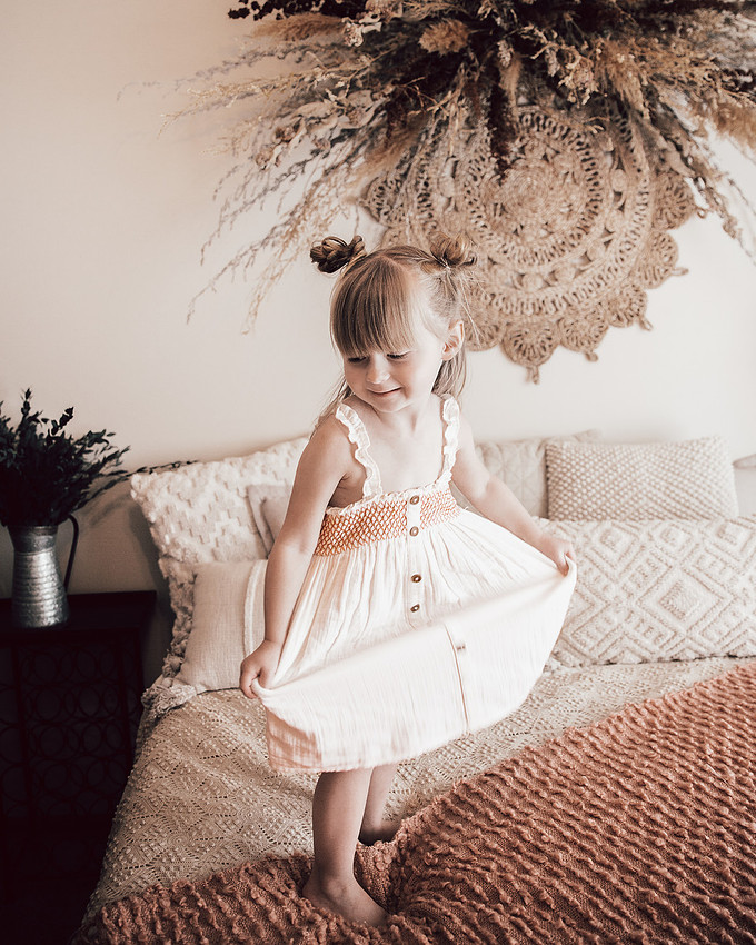 Girl milestone portrait dancing on neutral bed during lifestyle children photography session near Sioux Falls South Dakota
