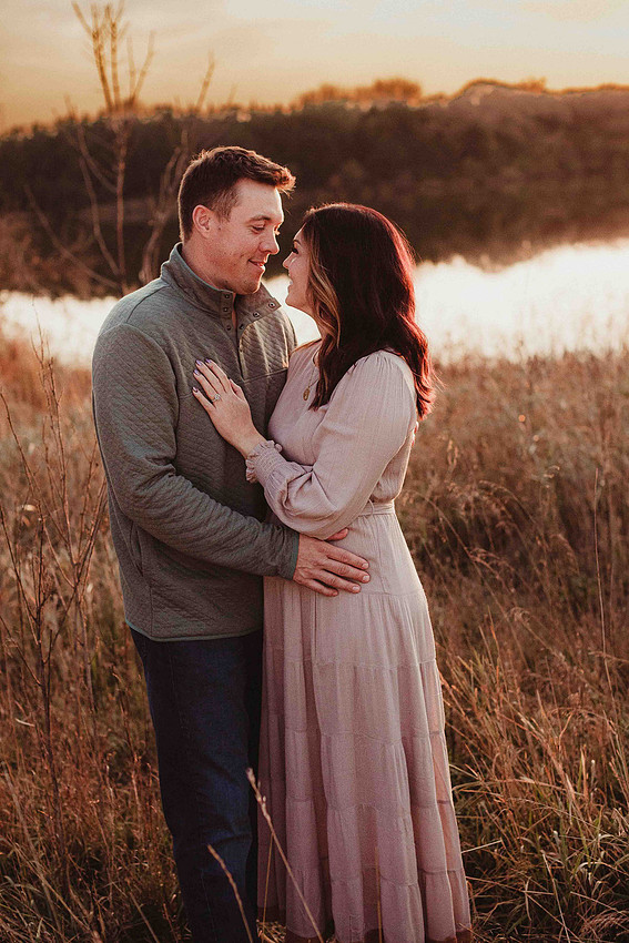 Husband pulling his wife close during a South Dakota sunset photo session, smiling with warm golden backlight creating a romantic and intimate atmosphere