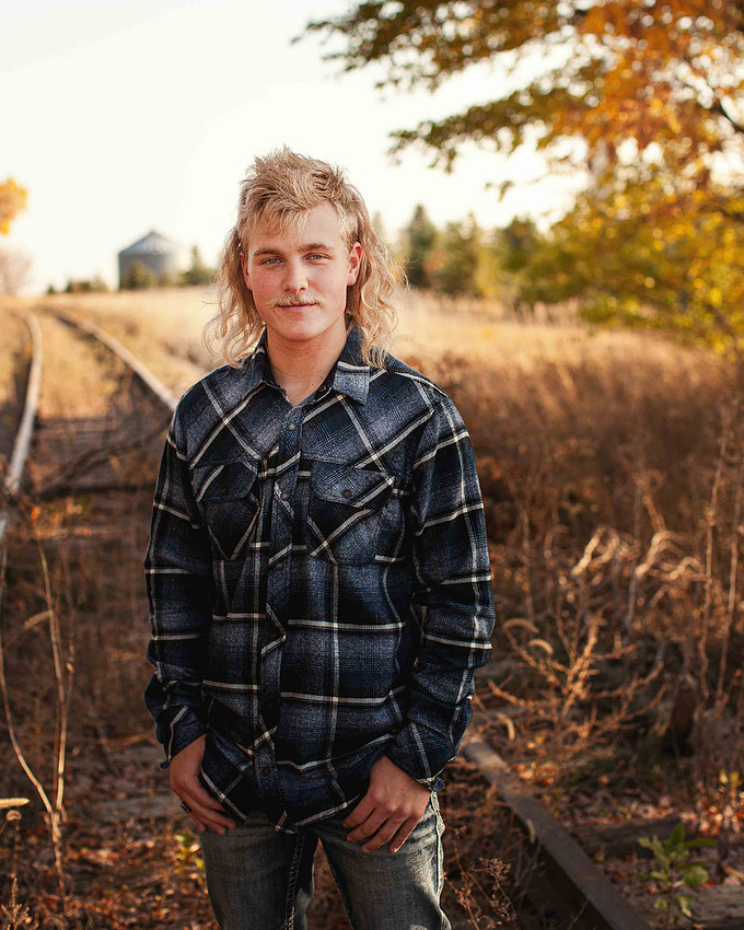 High school senior boy wearing a plaid flannel shirt during a fall sunset session in Sioux Falls, South Dakota, showing a calm and confident expression
