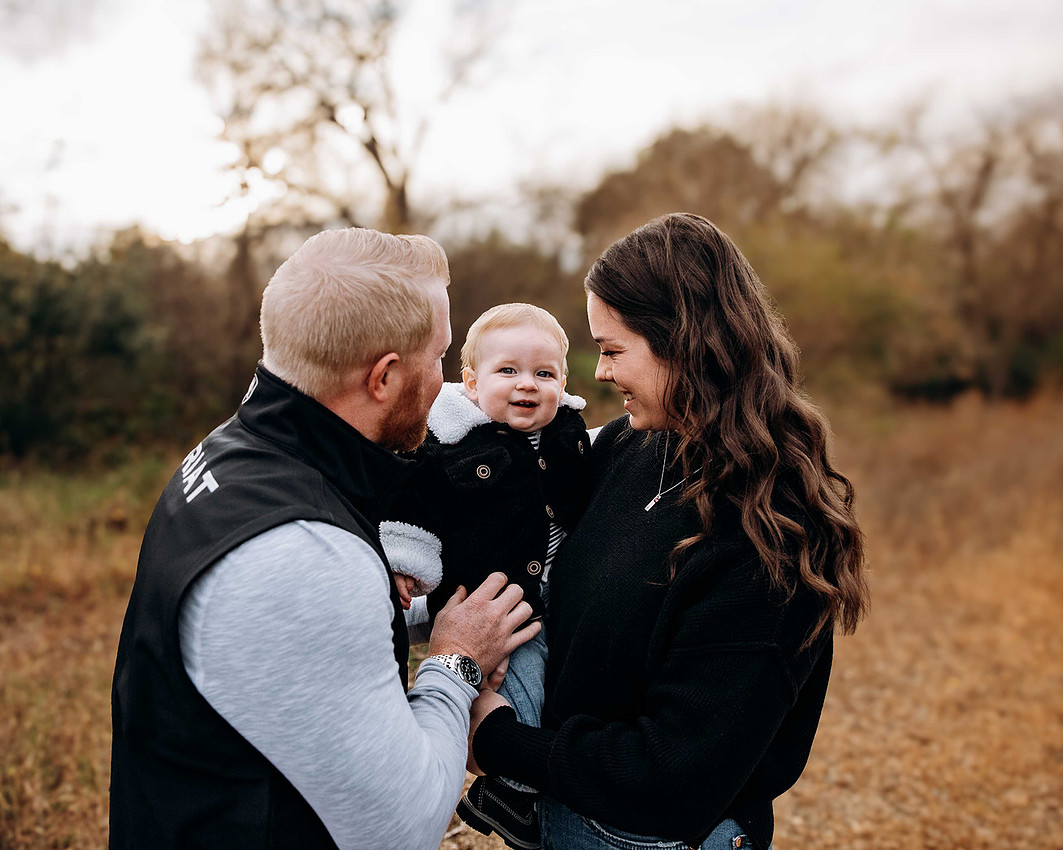 oung couple playing with their infant baby outdoors during a natural family photography session
