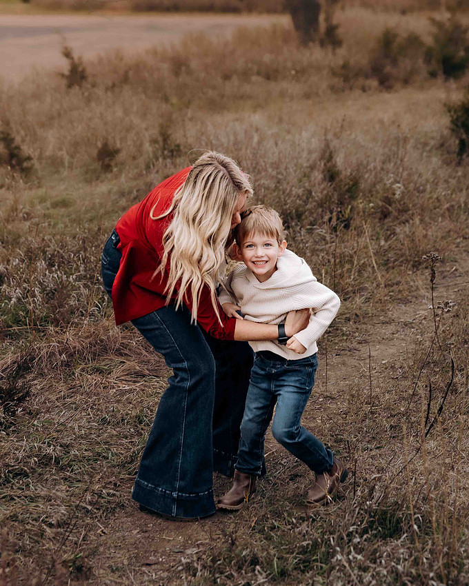 Mother playfully redirects her young son while walking on a path during a candid outdoor family session