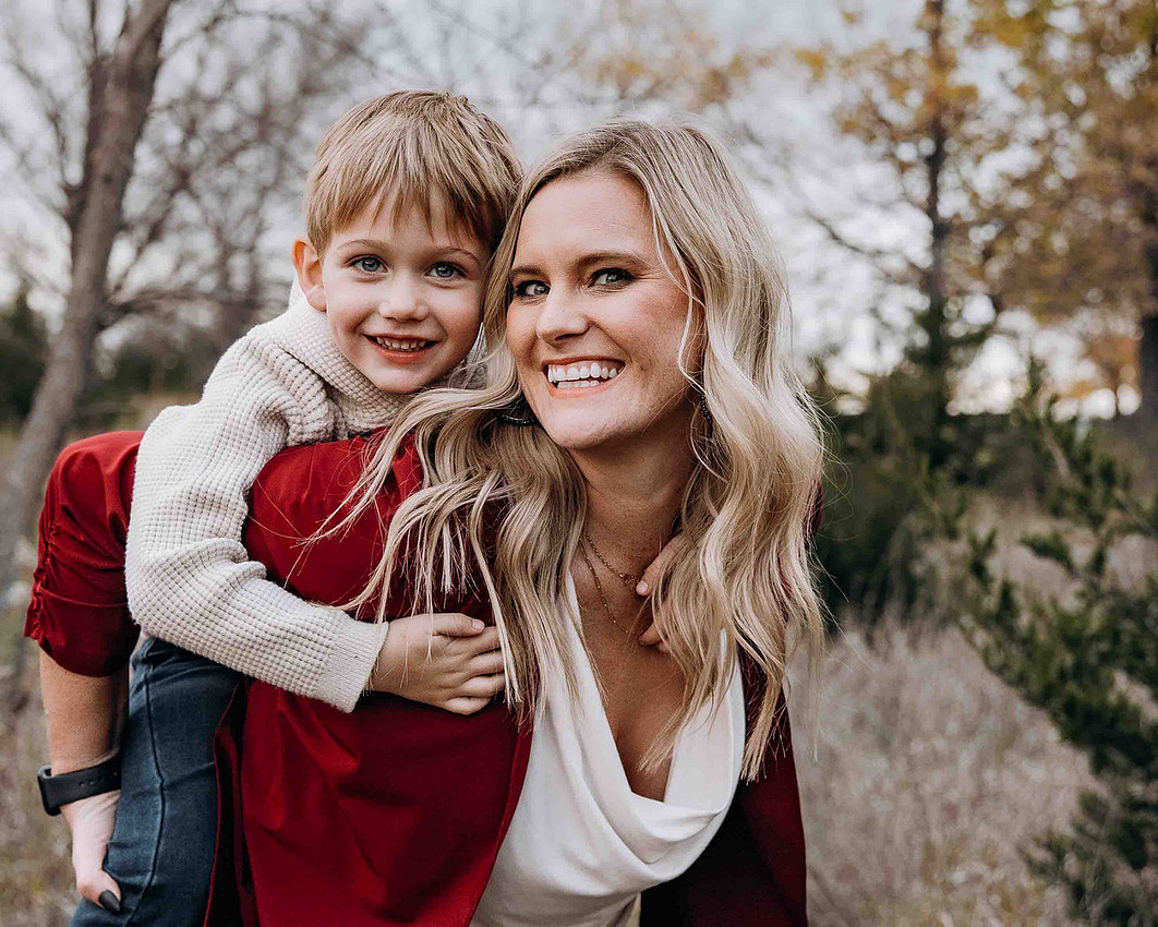Mother giving young son a piggyback ride during outdoor family photo session