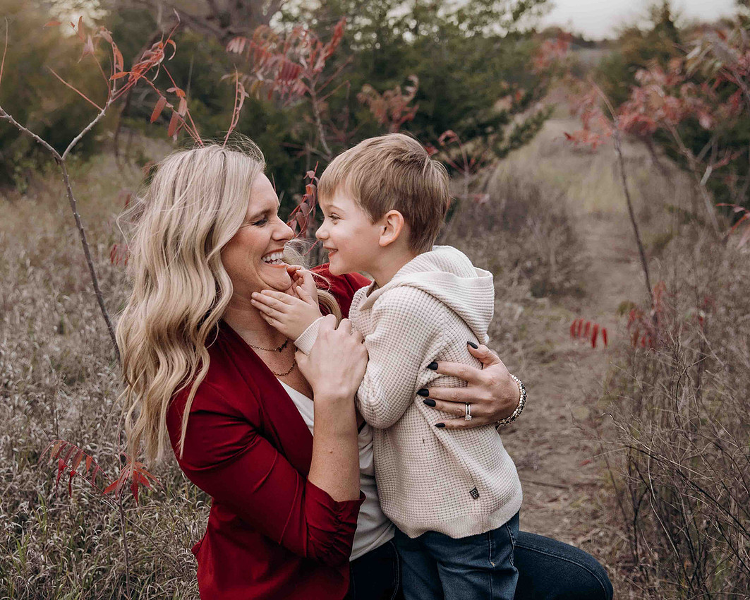 Mother and son smiling and laughing closely together during outdoor fall family session