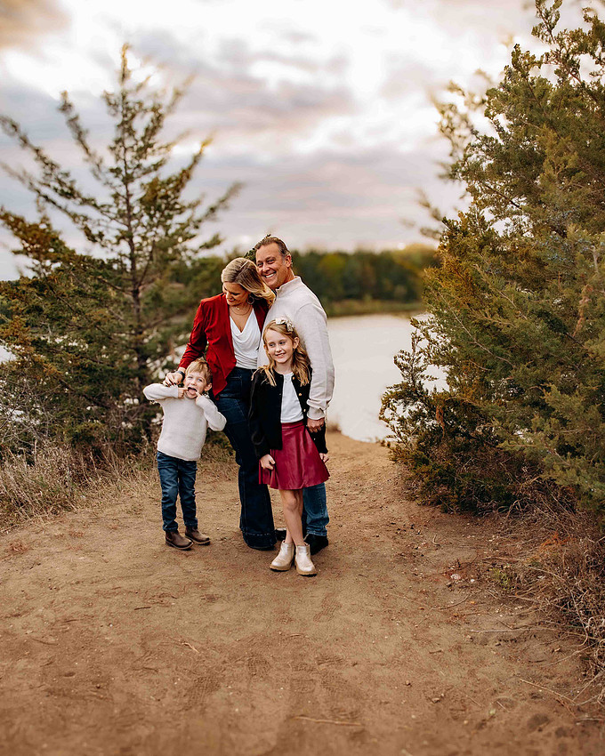 Family walking on a path near water with children being playful during outdoor fall photo session