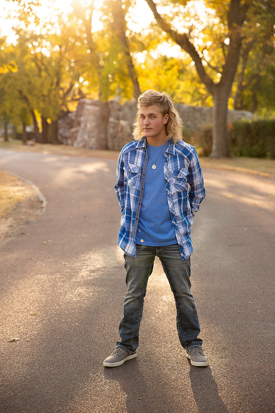 a boy in blue jeans posing during golden hour in Beresford South Dakota for senior portraits